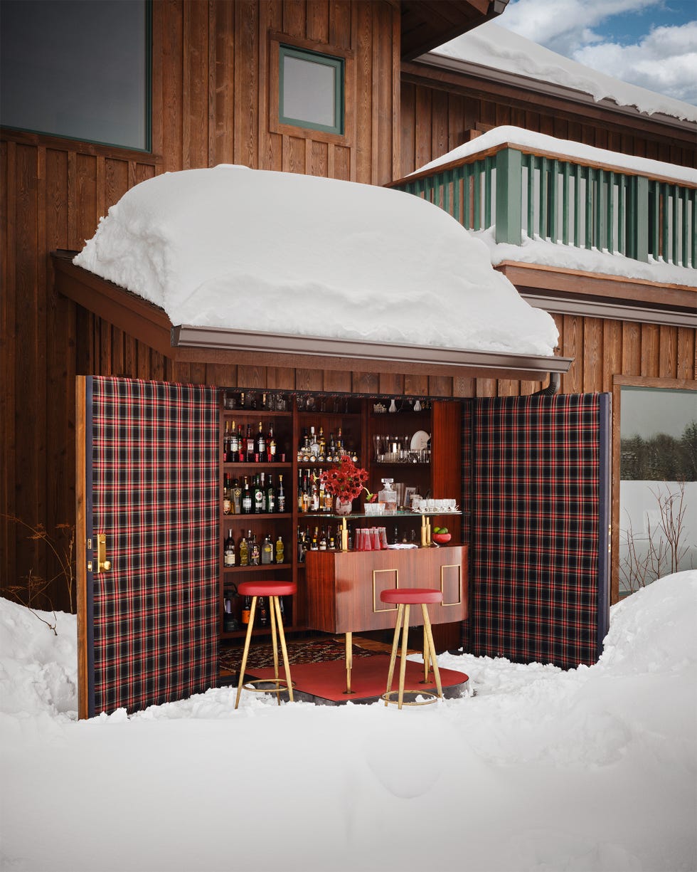 An outdoor bar area situated in a snowy environment, adjacent to a wooden structure.