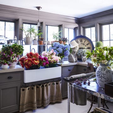 room with sink full of flowers, an oversized vintage clock, big windows, and a gray color palette