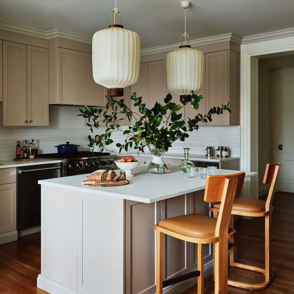 a kitchen with pendants that are lanterns and a large leafy bouquet, as well as bread and fruit on the table