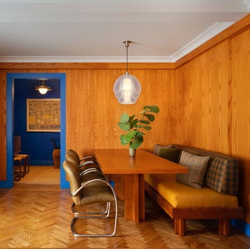 70s style apartment with wood paneled walls, leather seating, a quirky pendant, and a plant on the table