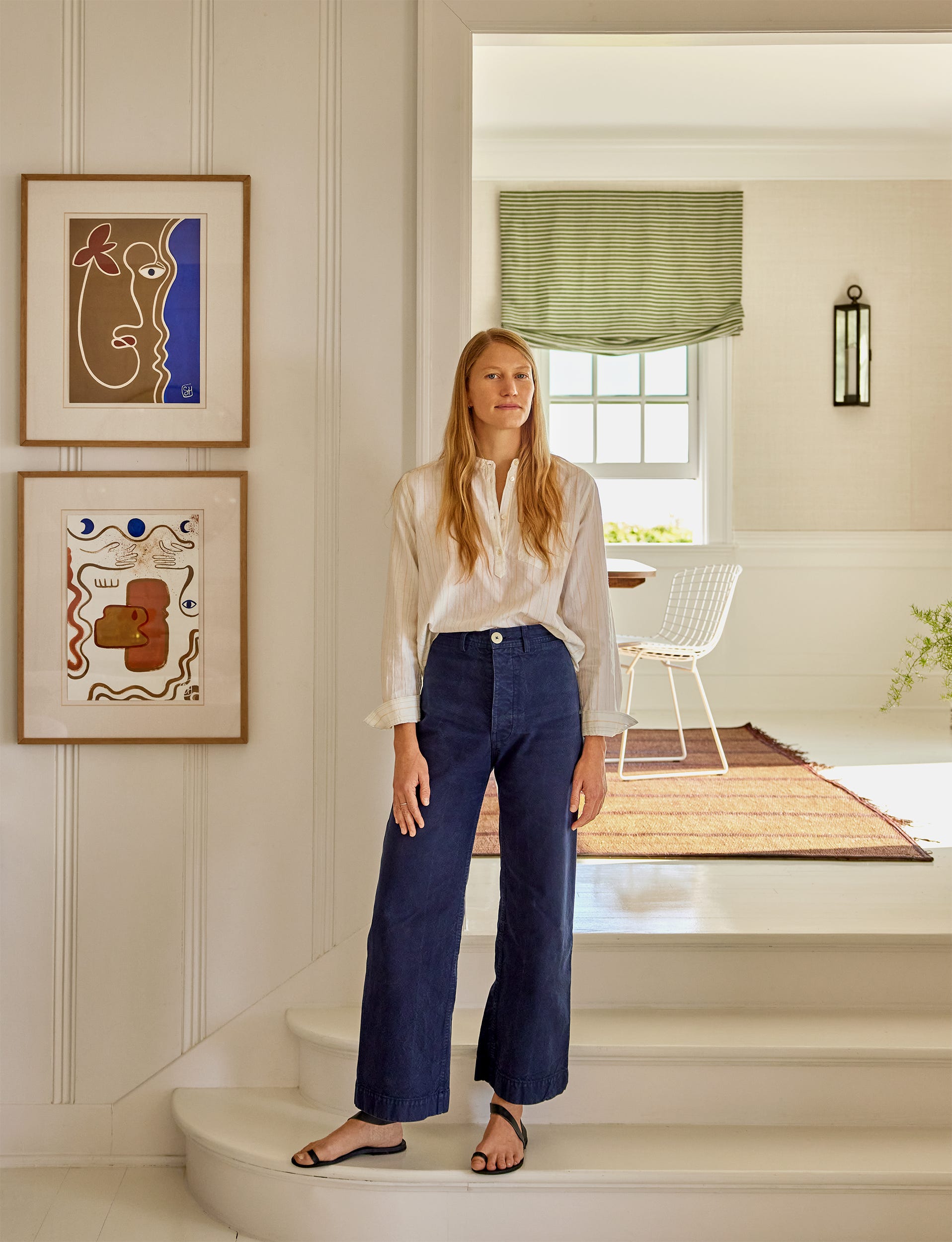 A person standing in a modern interior space with art on the walls.