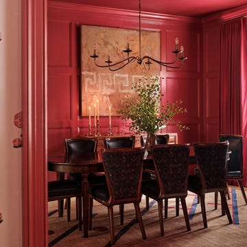 Dining room featuring a round table and upholstered chairs, with a bold red color scheme.