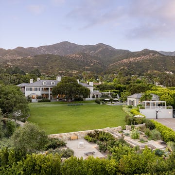 Spacious estate featuring a large lawn, tennis court, and surrounding mountains.