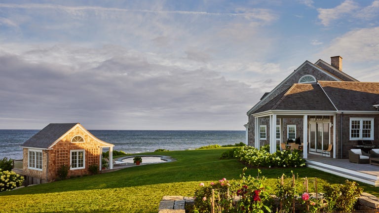Coastal property featuring a house, a small shed, and a landscaped garden.