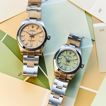 Two Rolex watches positioned on a colorful background of paint samples.