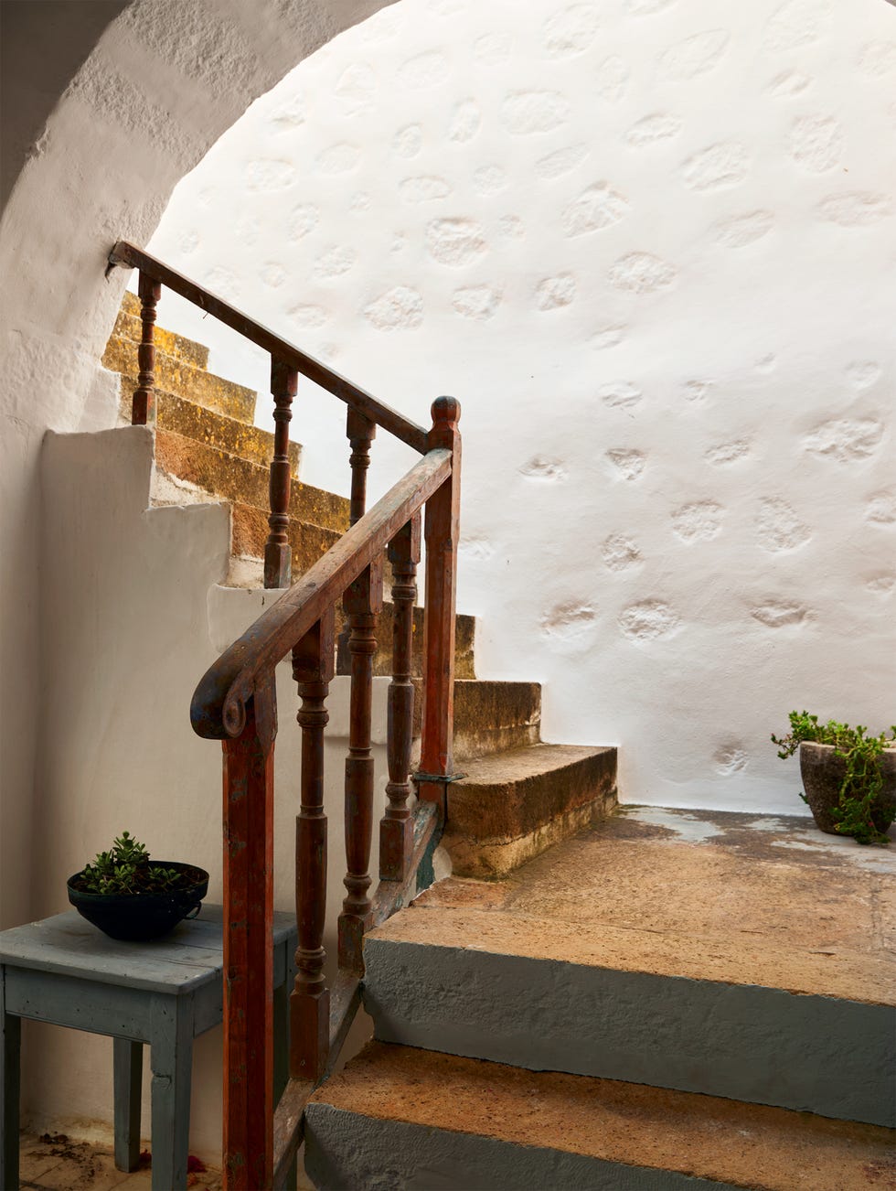 Stairs leading upward with a wooden railing and potted plants.