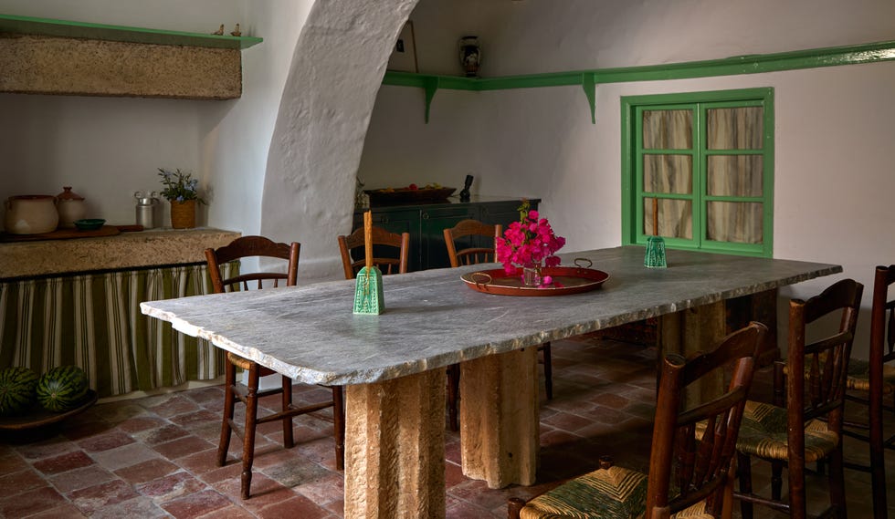 Interior dining area with a large stone table and wooden chairs.