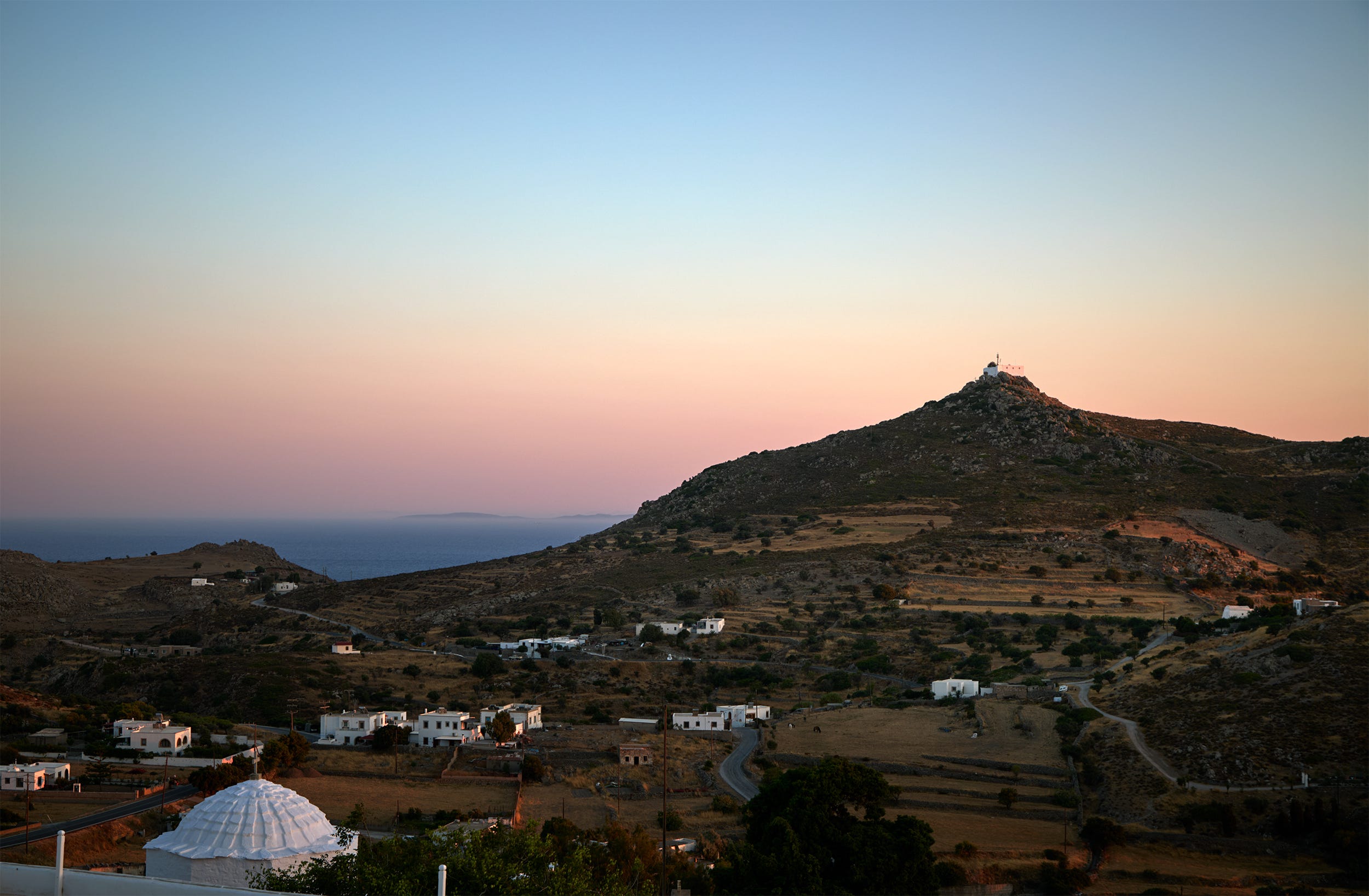 A panoramic view of a hilly landscape with a coastal background.