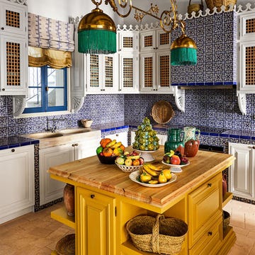 Brightly colored kitchen featuring an island with assorted fruits and decorative elements Brightly colored kitchen featuring an island with assorted fruits and decorative elements