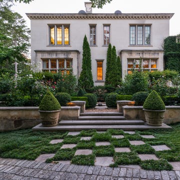 Elegant garden surrounding a house with lush vegetation and well-defined landscaping.