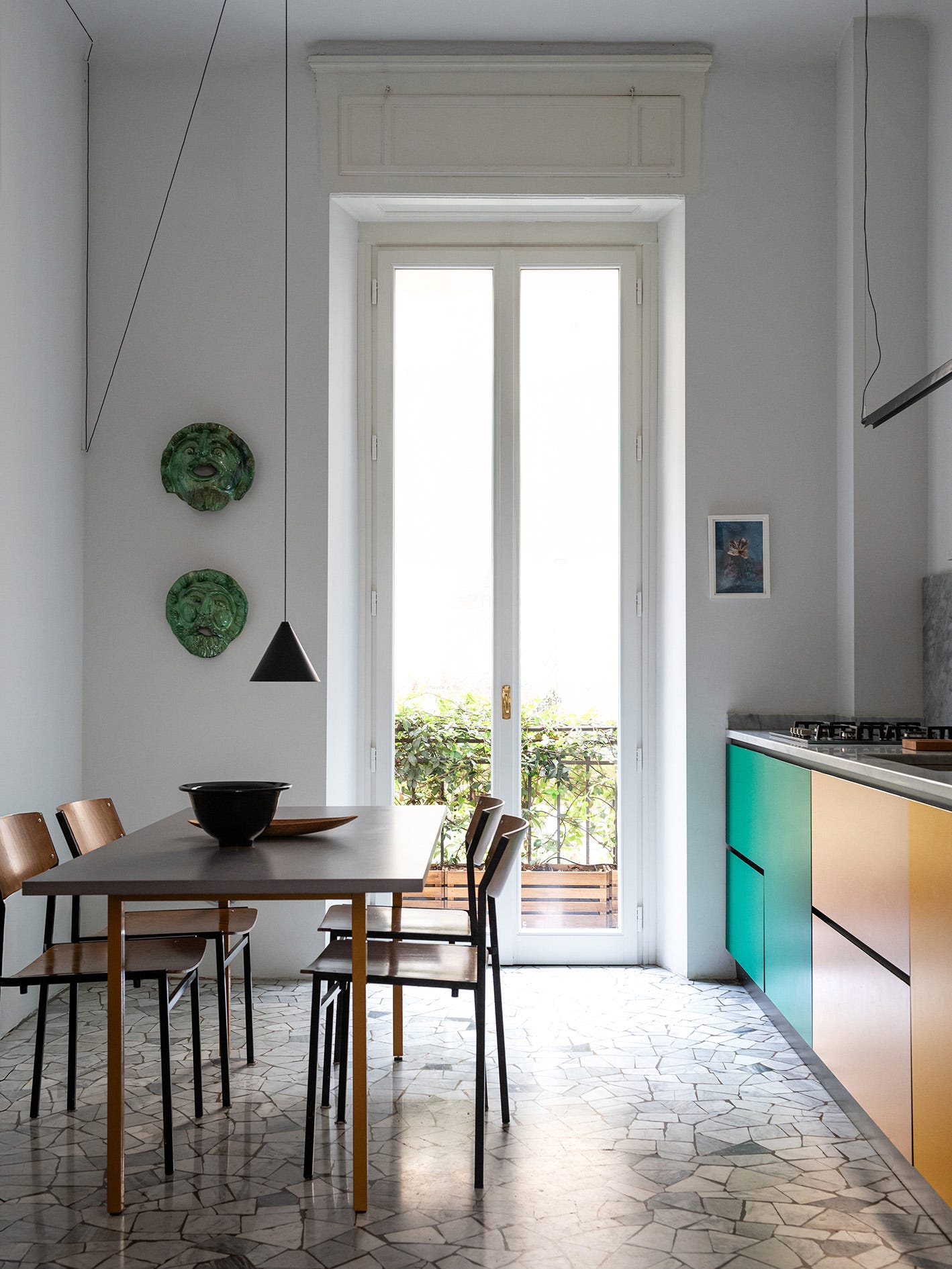 modern kitchen with dining area featuring a table and chairs, colorful cabinetry, and outdoor view.