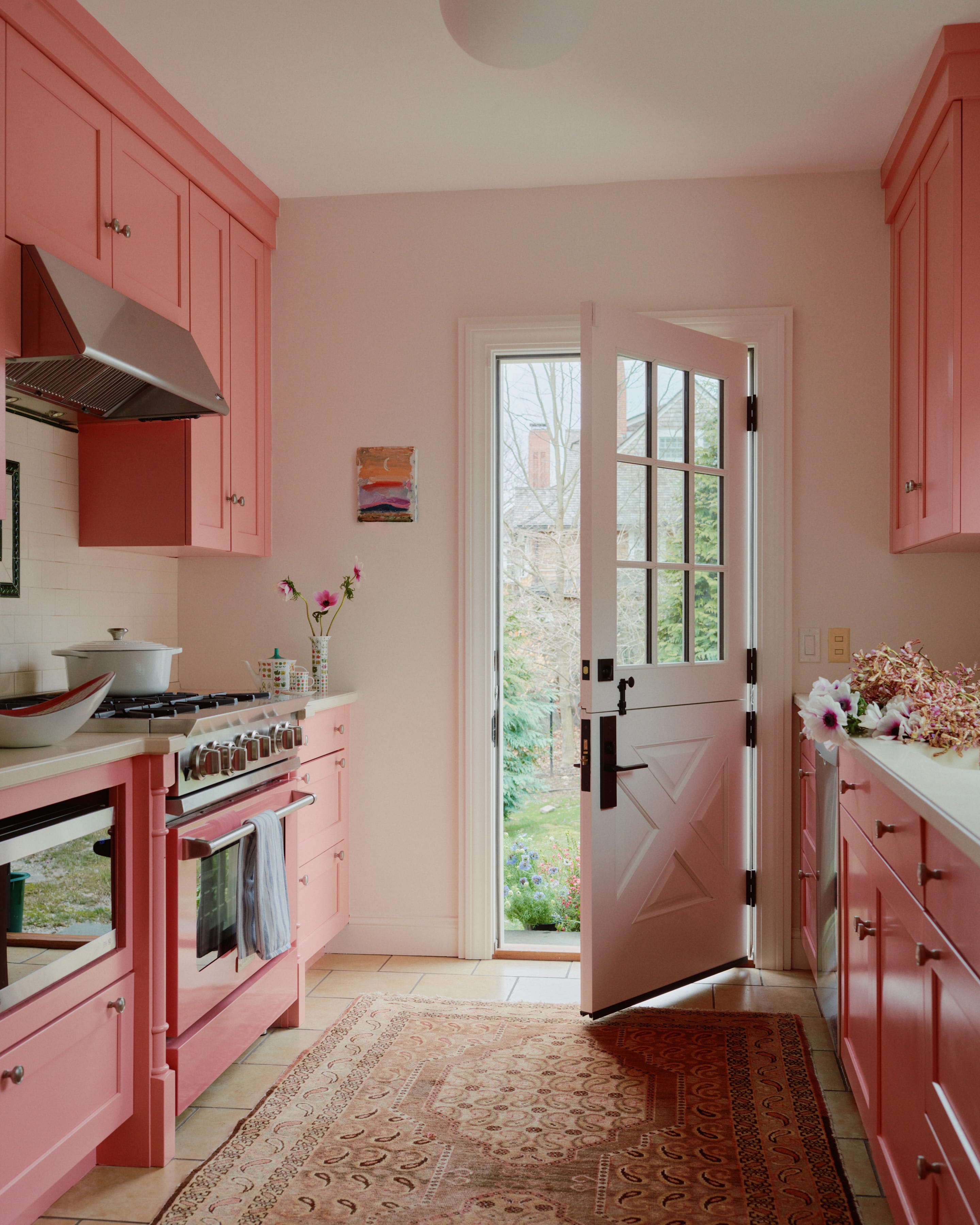 bright kitchen with pink cabinetry and an open door to the garden