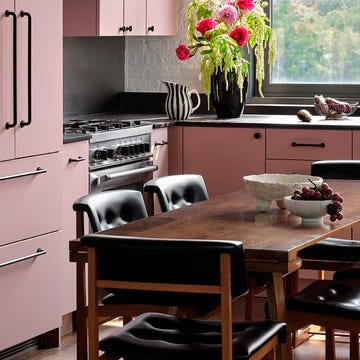 cocina con armarios rosas y encimera negra y con zona de comedor de estilo nordico