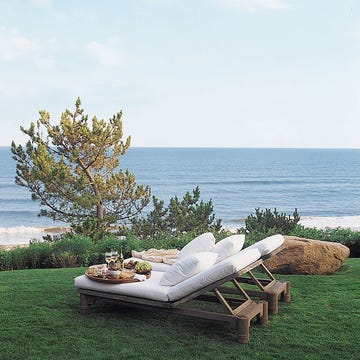 two wooden chaises with white cushions outside on the lawn
