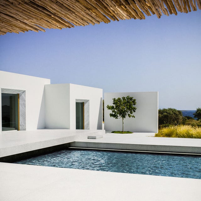 A-List 2024 - ELLE DECOR a modern white block house with a pool and views of the ocean beyond