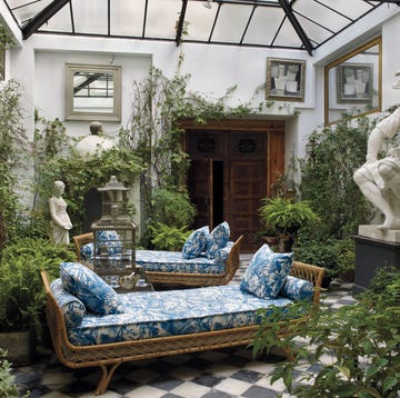 interior courtyard with two blue and white upholstered daybed and checked floor and glass panels overhead and lots of plants