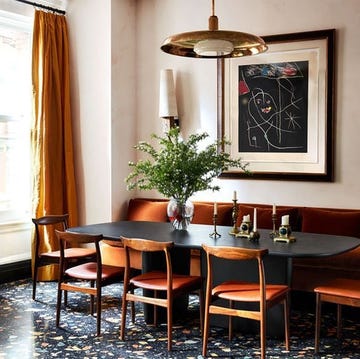 dining area with long dark orange leather banquette and matching chairs pulled up to a dark wood table with rounded corners