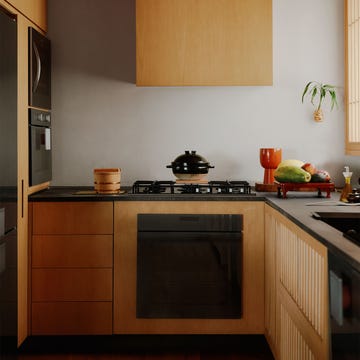 kitchen with wood cabinetry and black countertop and appliances, putty colored wall, covered rice pot on stove, vegetables on a tray on counter, wood plank floor, ribbed wood ceiling