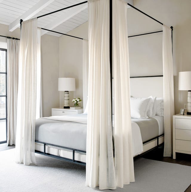 A-List 2024 - ELLE DECOR a four poster bed with white bed curtains and a large square rug