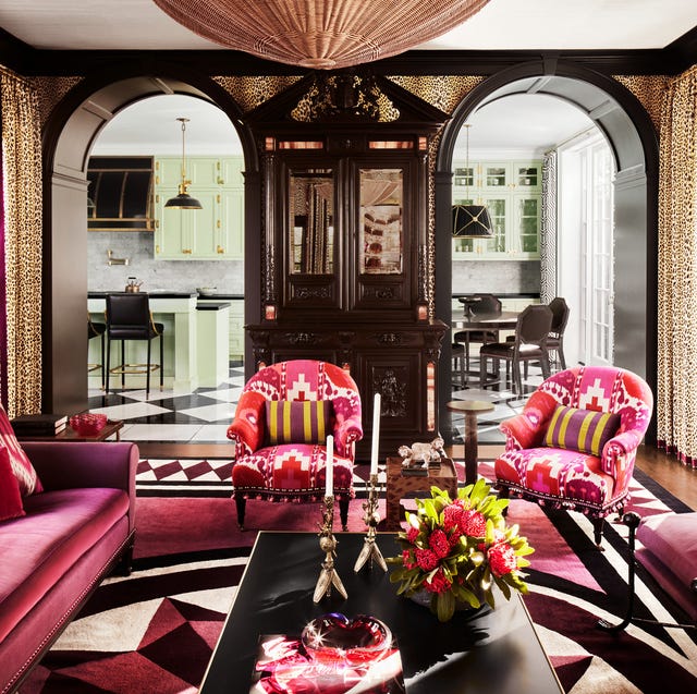 A-List 2024 - ELLE DECOR dramatic living room with rounded archways and red patterned modern southwest upholstery on chairs and a plum red velvet on the sofa and a long black cocktail table and a large domed light fixture at top