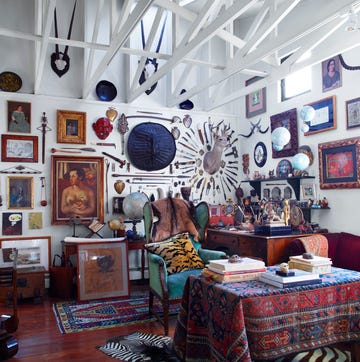 A cluttered and eclectic room filled with various artworks and decorative objects
