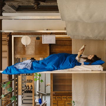 person relaxing in a lofted bed in a cozy room with wooden elements and plants