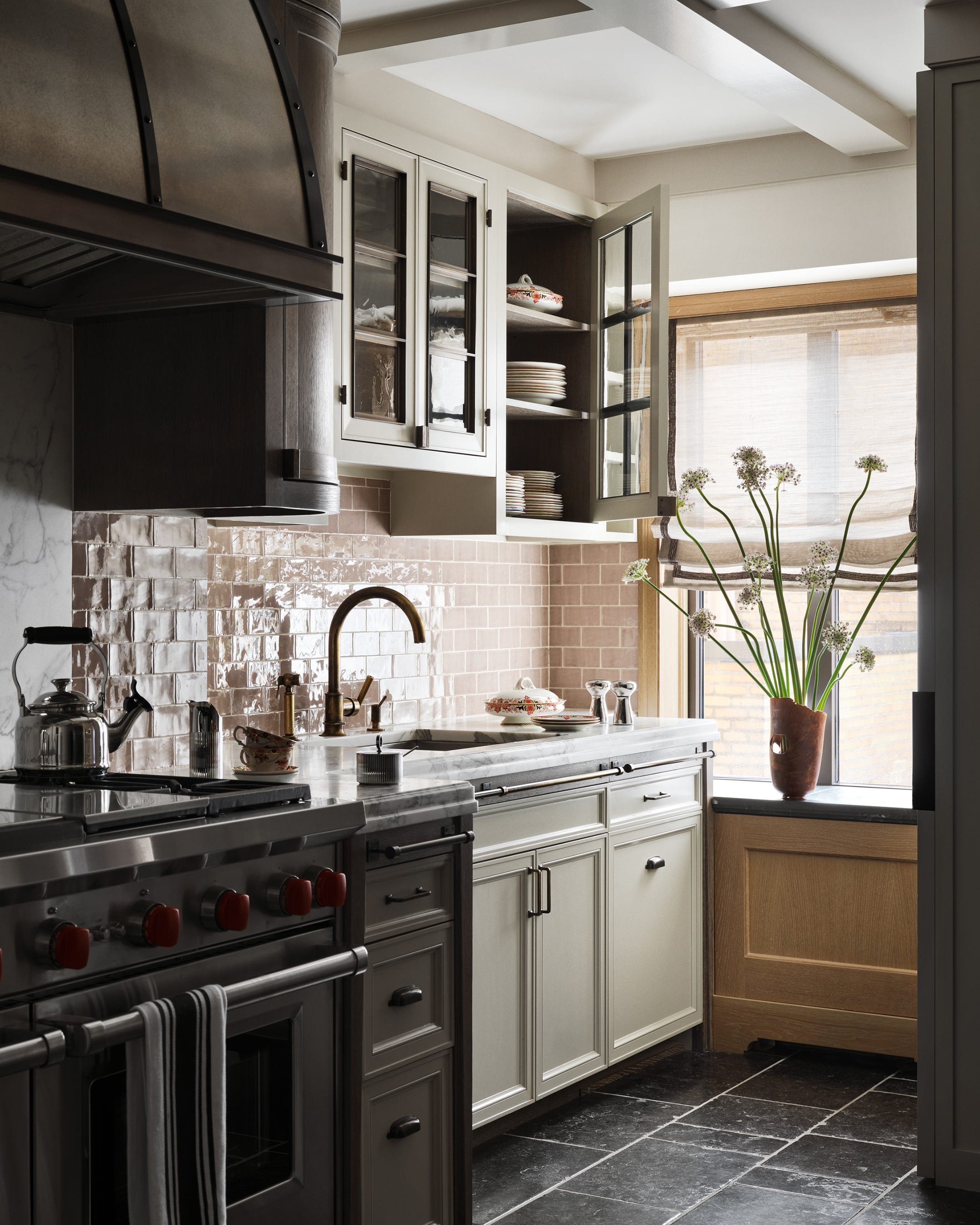 Modern kitchen featuring a stove, sink, and window with plants.