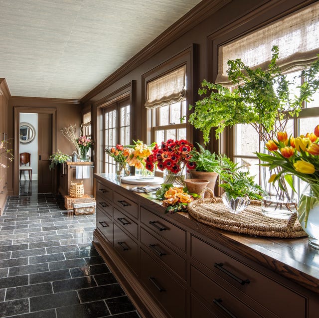 A-List 2024 - ELLE DECOR a kitchen with a countertop full of flowers in various containers and a gray tile floor