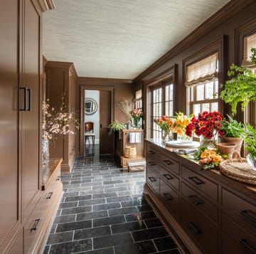 A-List 2024 - ELLE DECOR a kitchen with a countertop full of flowers in various containers and a gray tile floor