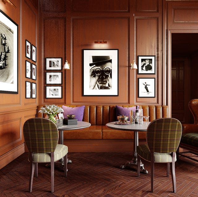 A-List 2024 - ELLE DECOR wood paneled dining area with framed photos on the the wall and with a leather banquette and upholstered chairs and two small pedestal table