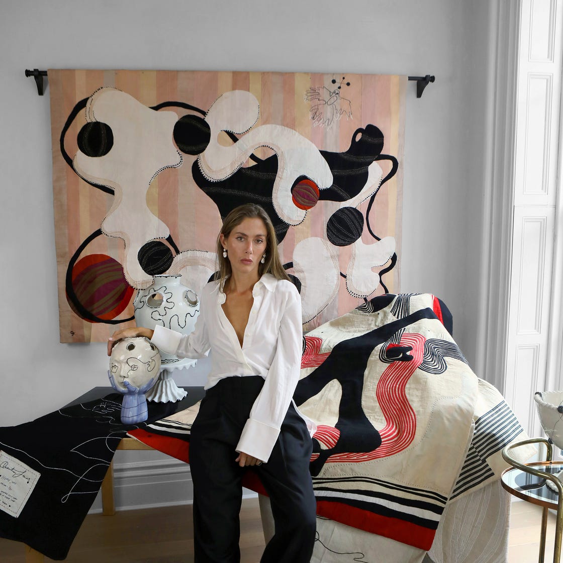 artist quentin jones sits with tapestries and sculptures.