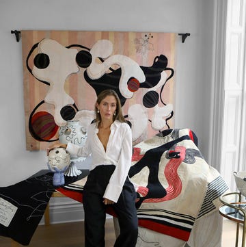artist quentin jones sits with tapestries and sculptures.