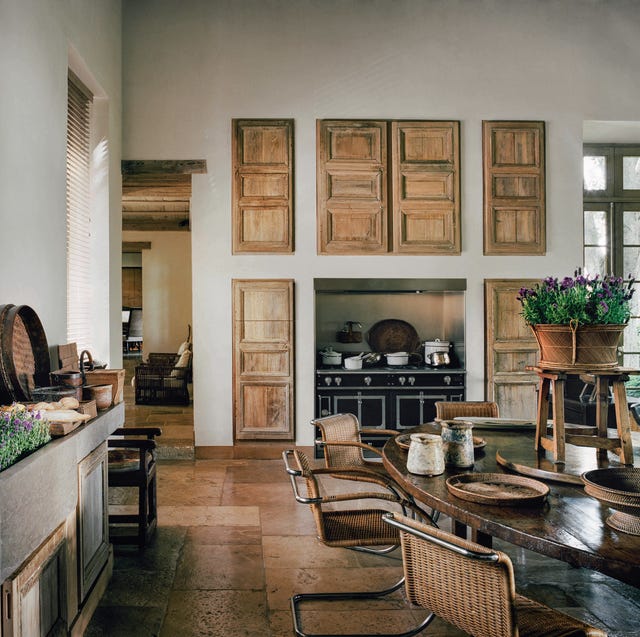 A-List 2024 - ELLE DECOR a dining kitchen area with a large table and on the back wall are wooden doors over an expensive black range
