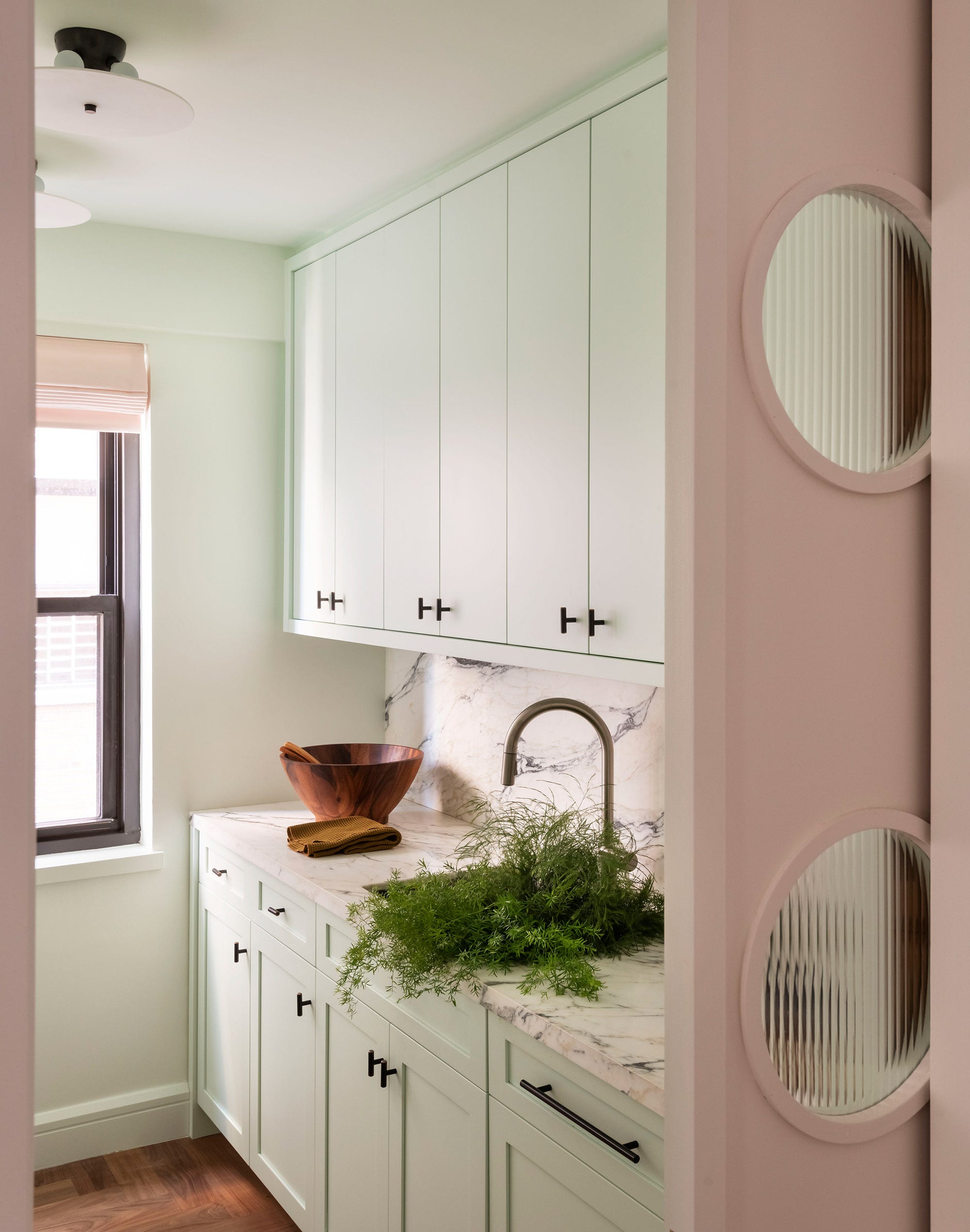 manhattan apartment kitchen with pastel cabinetry and a marble backsplash