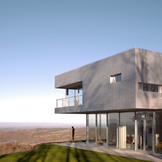 A-List 2024 - ELLE DECOR a person standing outside a modern concrete building on a hill