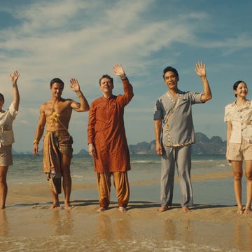 group of people standing on a beach waving their hands