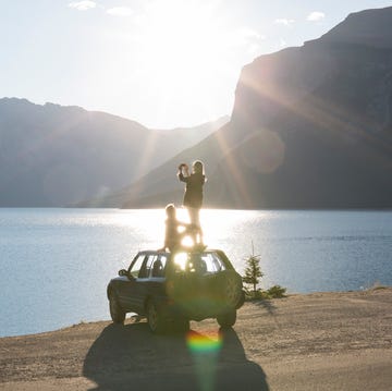 woman takes pic from car roof while man relaxes
